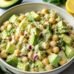 Creamy chickpea and avocado salad in a bowl with fresh ingredients.