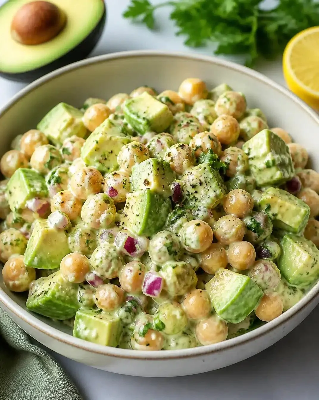 Creamy chickpea and avocado salad in a bowl with fresh ingredients.