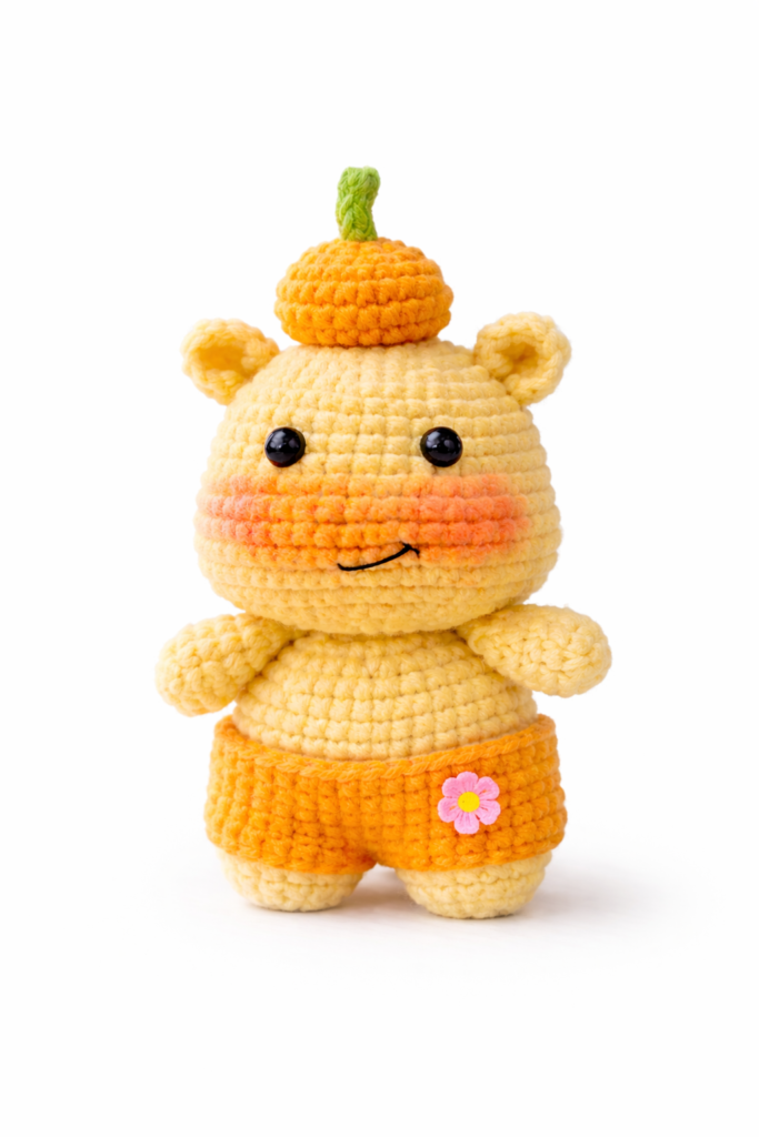 Lulu the Capy-Hippo amigurumi on white background with mini pumpkin — capybara crochet pattern free.