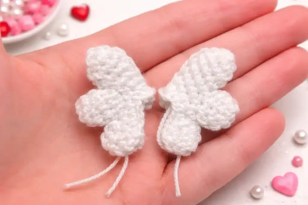 Crochet heart pattern free Valentine heart plush shown as two finished versions: the Angel heart with white wings and the Devil heart with horns and tail, displayed in a hand for size reference.