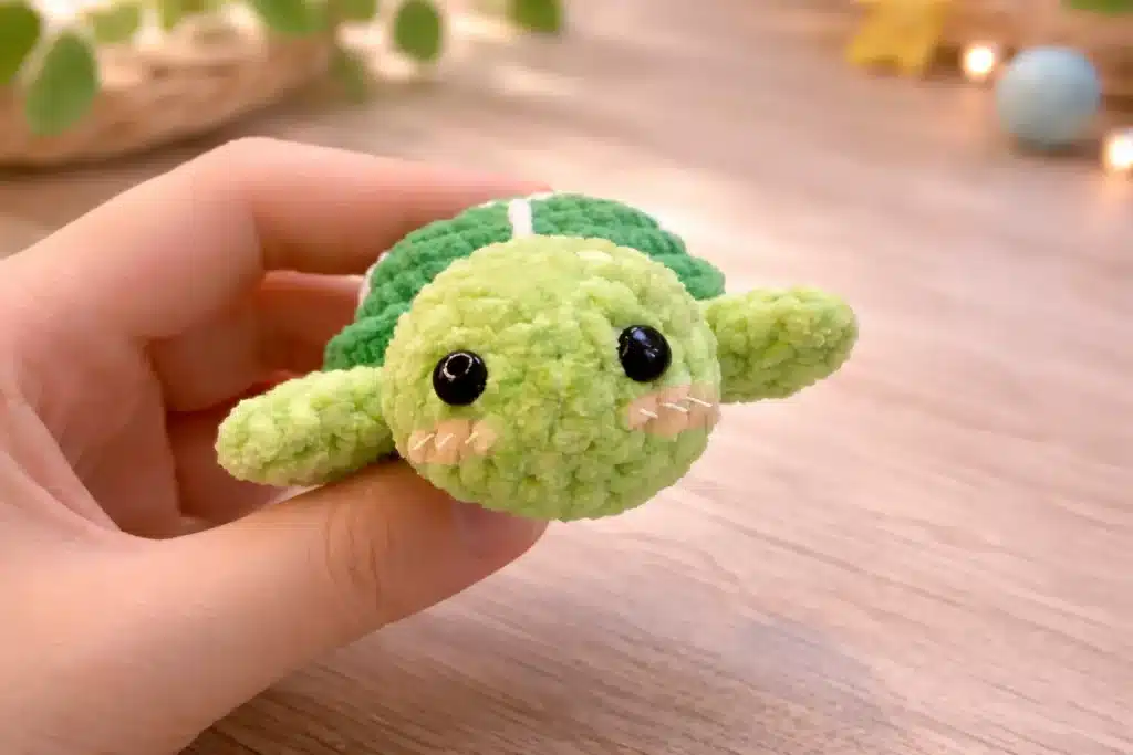 Mini sea turtle pattern close-up with safety eyes and plush green crochet flippers