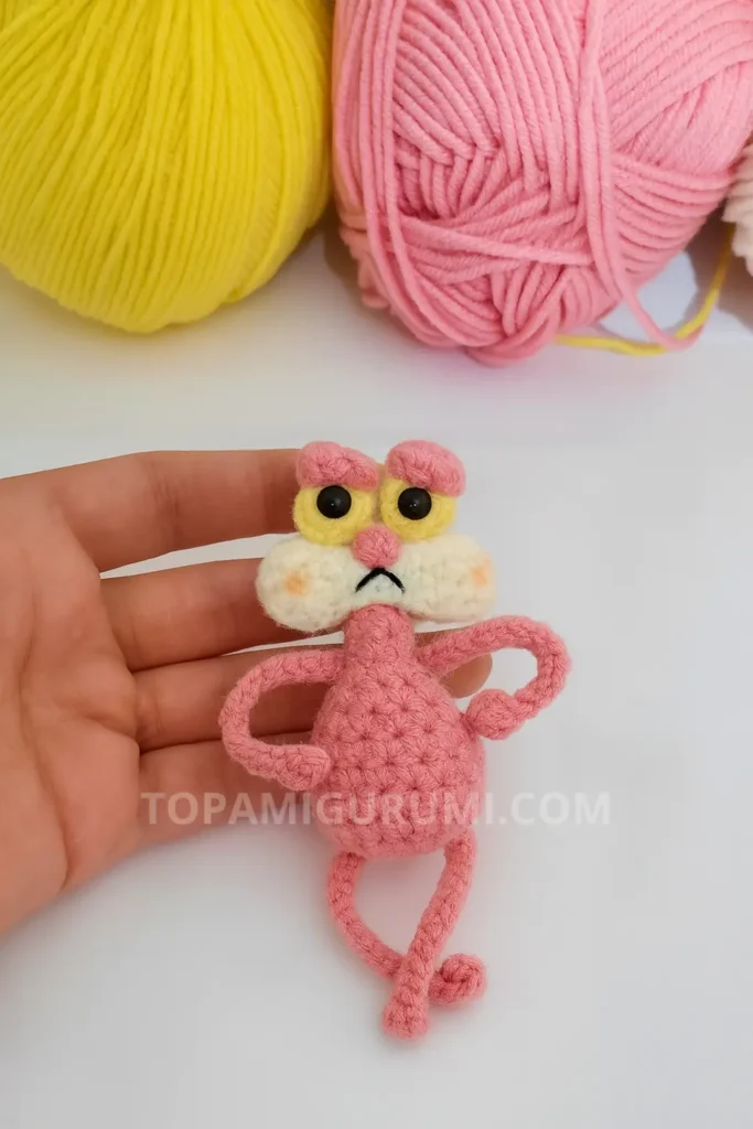 pink cat amigurumi pattern free small toy held in hand with yellow and pink yarn